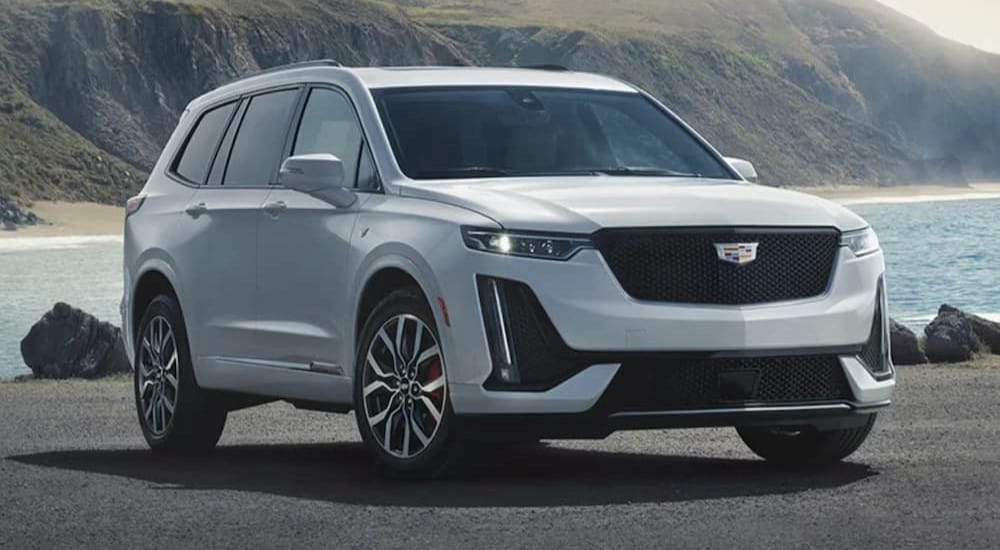 A white 2024 Cadillac XT6 is shown parked near a lake.
