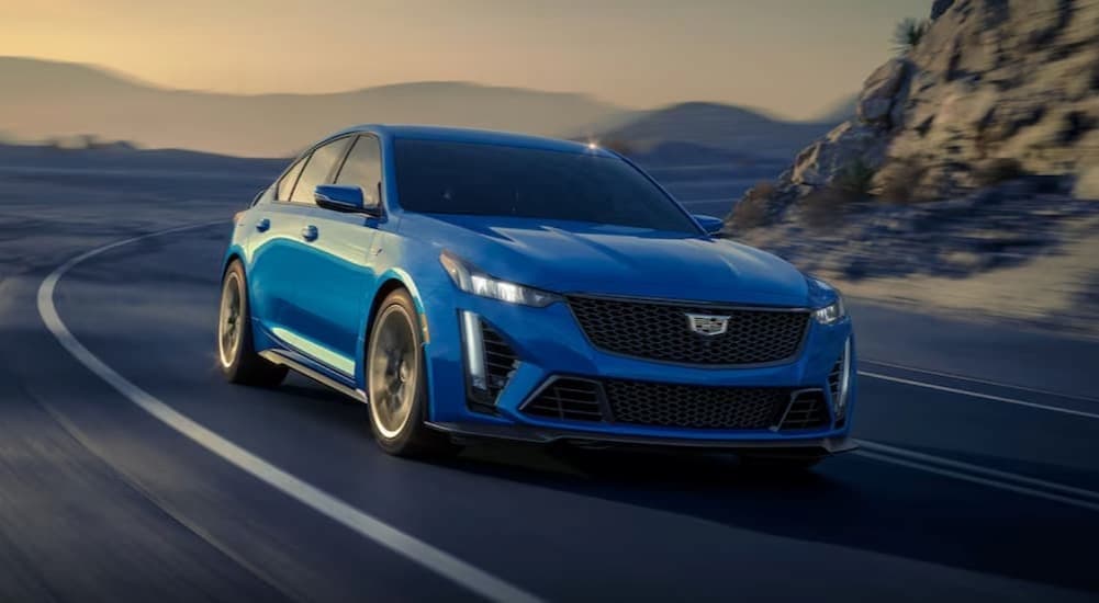 A blue 2024 Cadillac CT5-V Blackwing is shown driving on a highway.