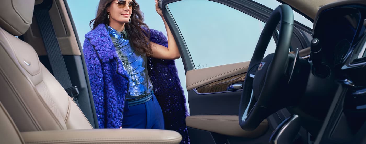 A woman is opening the driver's side door of a 2025 Cadillac XT6.