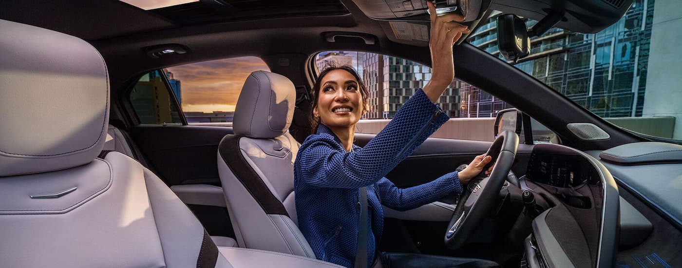 A woman is opening the sunroof in a 2025 Cadillac XT4.