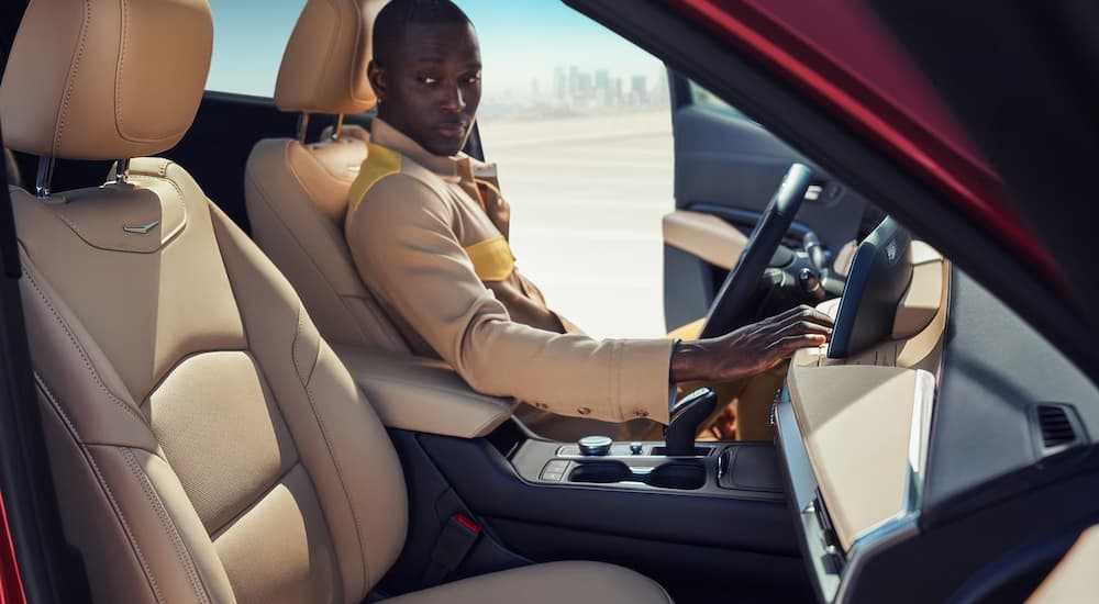 A man is shown sitting in the front seat of a 2024 Cadillac XT4 for sale.