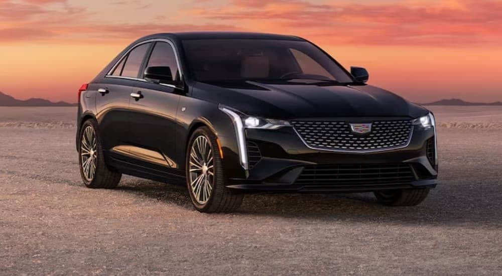 A black 2024 Cadillac CT4 is shown parked off-road.
