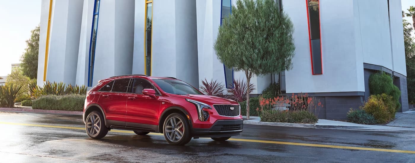 A red 2023 Cadillac XT4 is shown driving on a city street after leaving a Cadillac dealer in New York City.