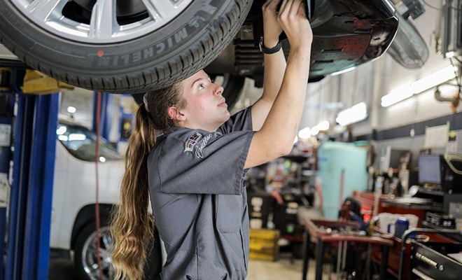 A certified Cadillac technician working on a cadillac vehicle in a service bay at Cadillac of South Charlotte