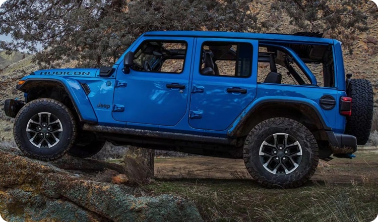 Blue Jeep Wrangler driving above terrain