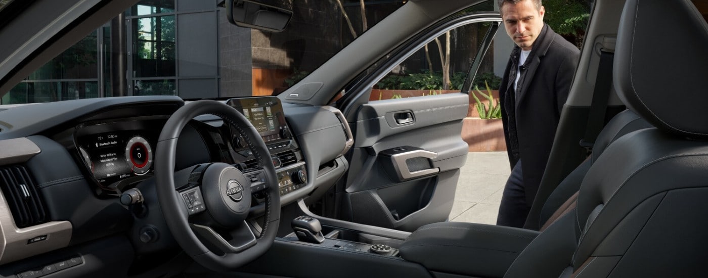 A man getting into the passenger side of a 2025 Nissan Pathfinder.