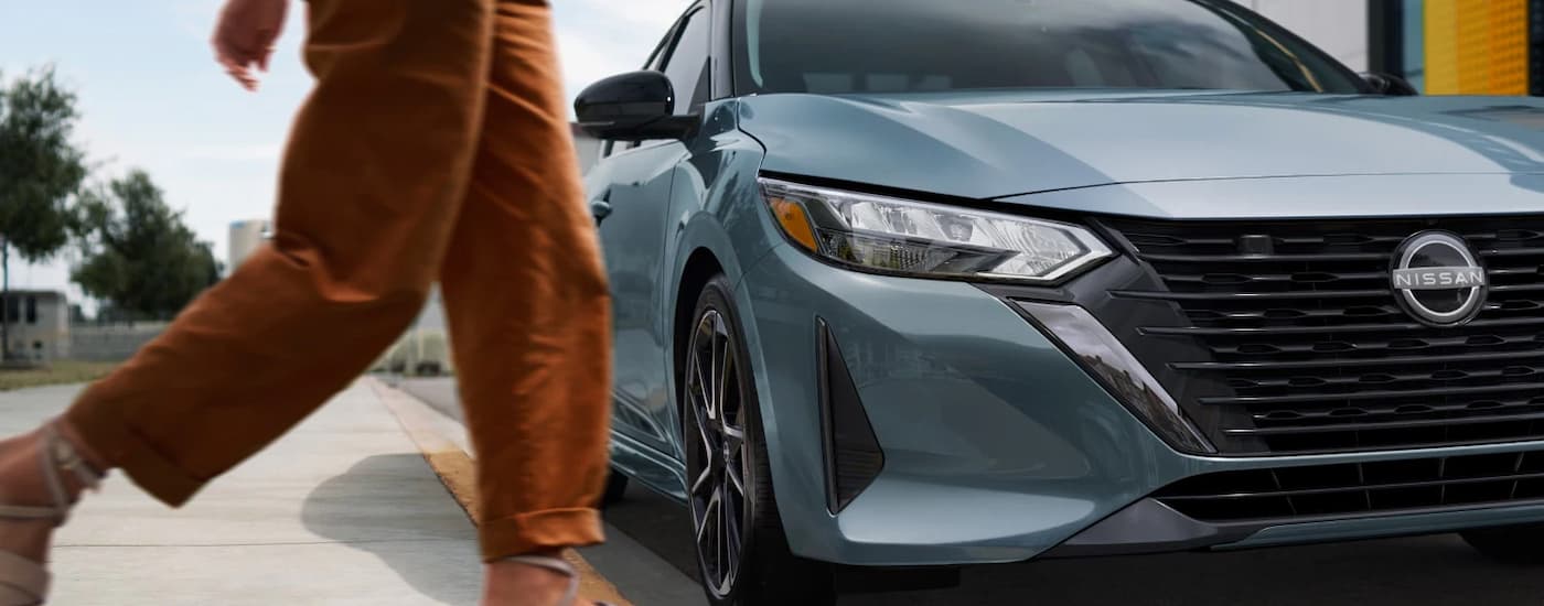 Person walking past a parked grey 2025 Nissan Sentra.