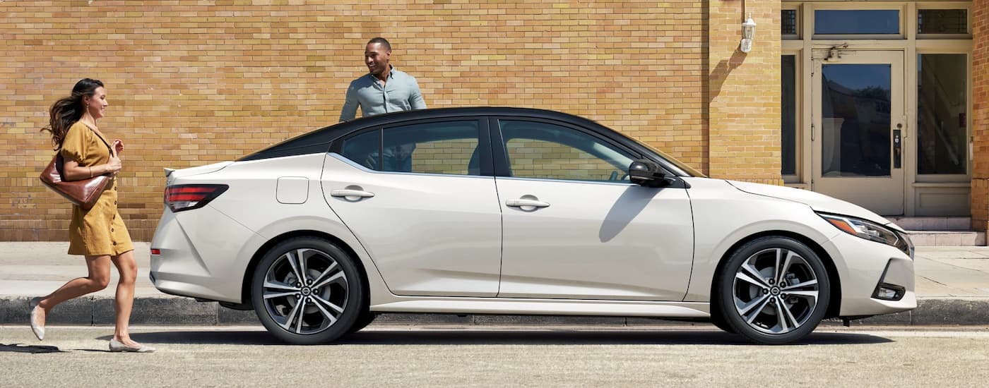A white 2023 Nissan Sentra parked on the side of a city street.