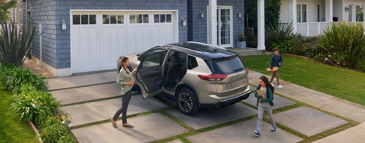 A tan 2025 Nissan Rogue is shown from the rear at an angle.