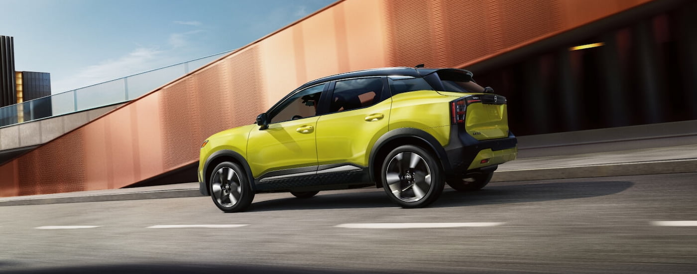 Side of a yellow 2026 Nissan Kicks SR driving down a road.