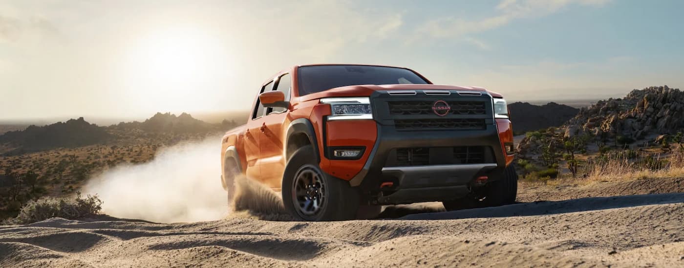 Orange 2026 Nissan Fronteir off-roading on a dusty trail