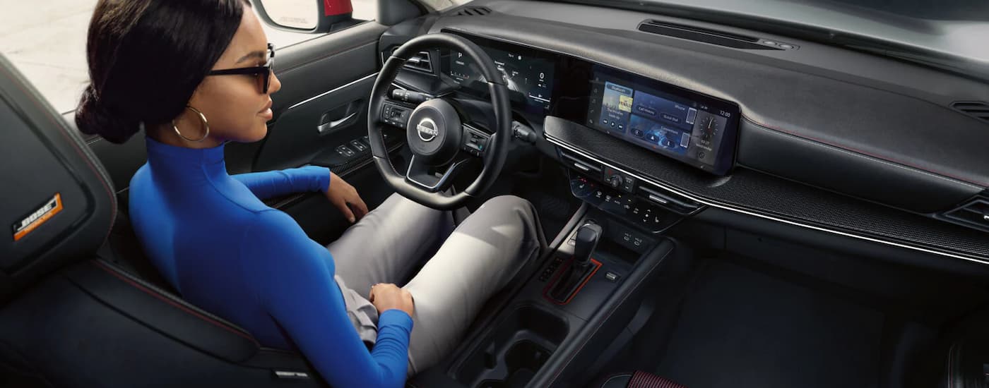 A woman is driving in a 2025 Nissan Kicks SR for sale.