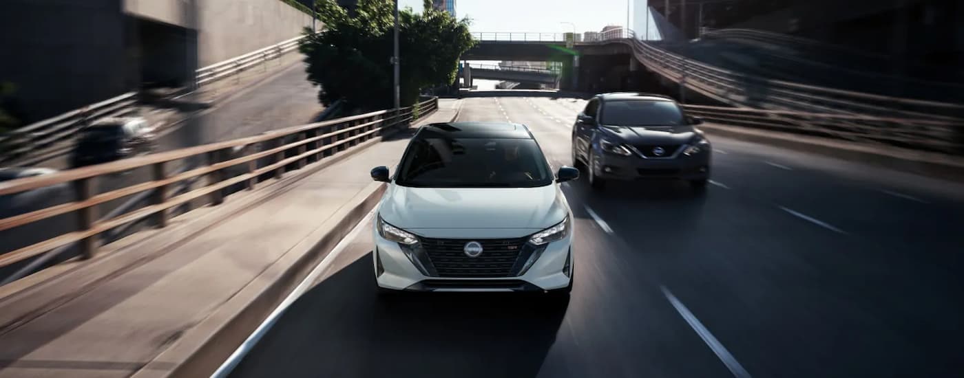 A white 2025 Nissan Sentra SR driving on a city highway after leaving a Nissan dealer.