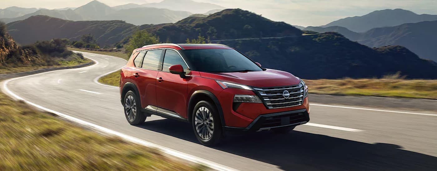 Red 2025 Nissan Rogue driving on a mountain road