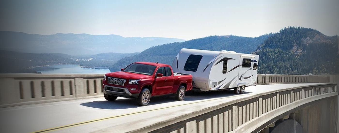 A red 2024 Nissan Frontier towing a camper
