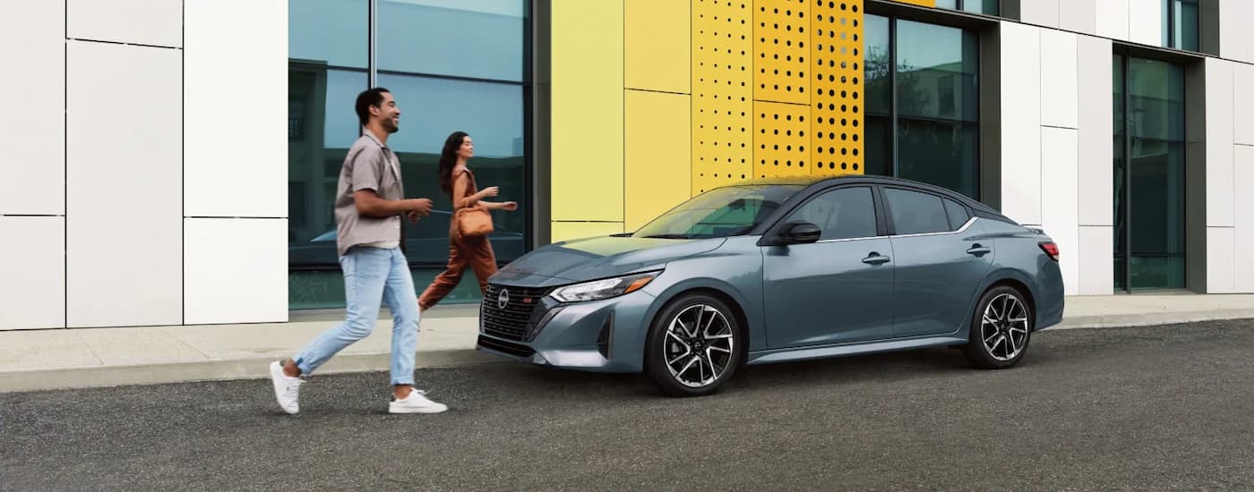 Two people walking towards a grey 2025 Nissan Sentra