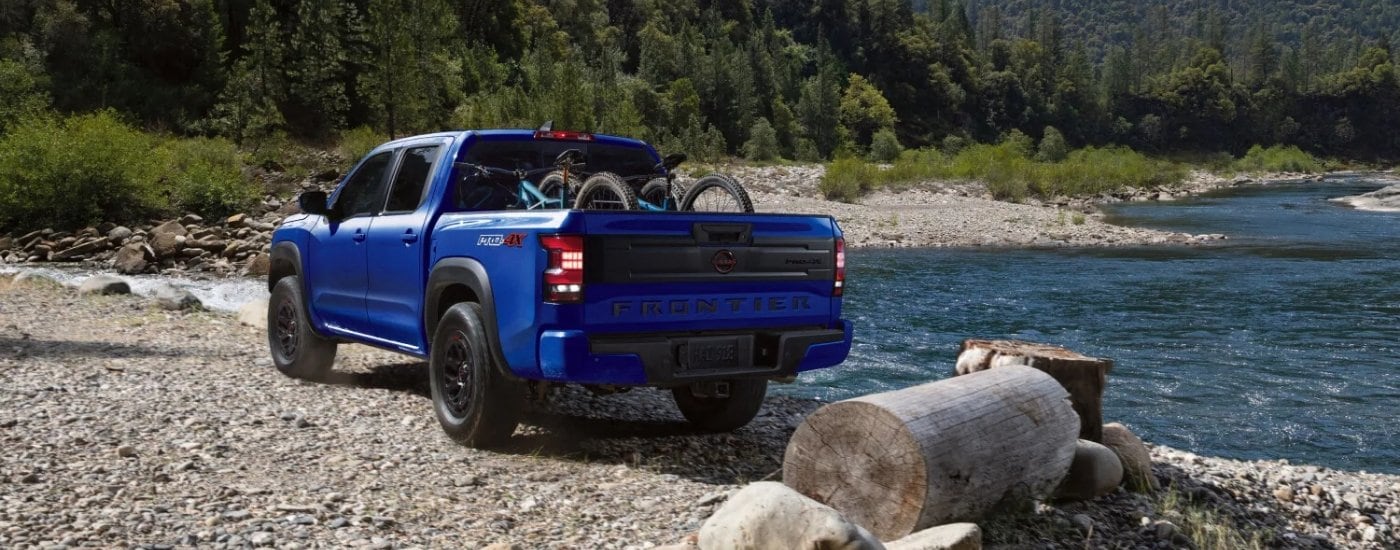 A blue 2025 Nissan Frontier PRO-4X parked off-road near water