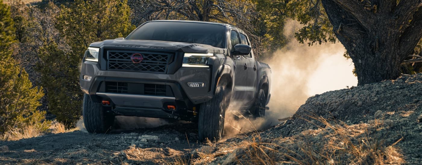 A gray 2022 Nissan Frontier driving off-road on a dirt trail
