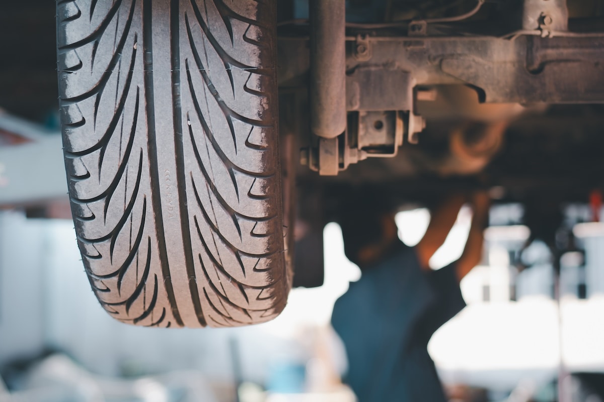 Closeup of a car tire with a repair shop in the background.