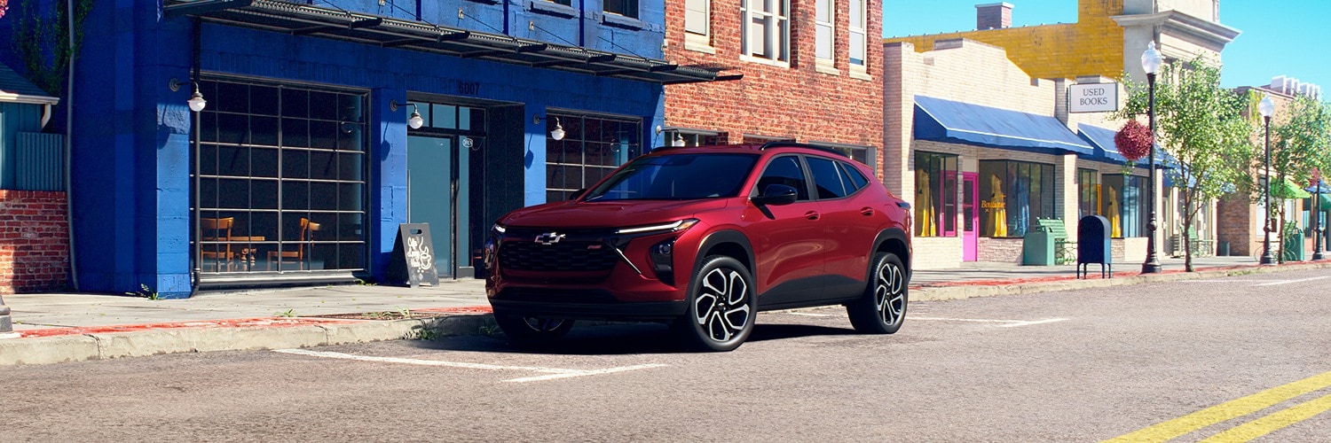 Red 2025 Chevrolet Trax parked on a desert
road next to mountain terrain and cacti
