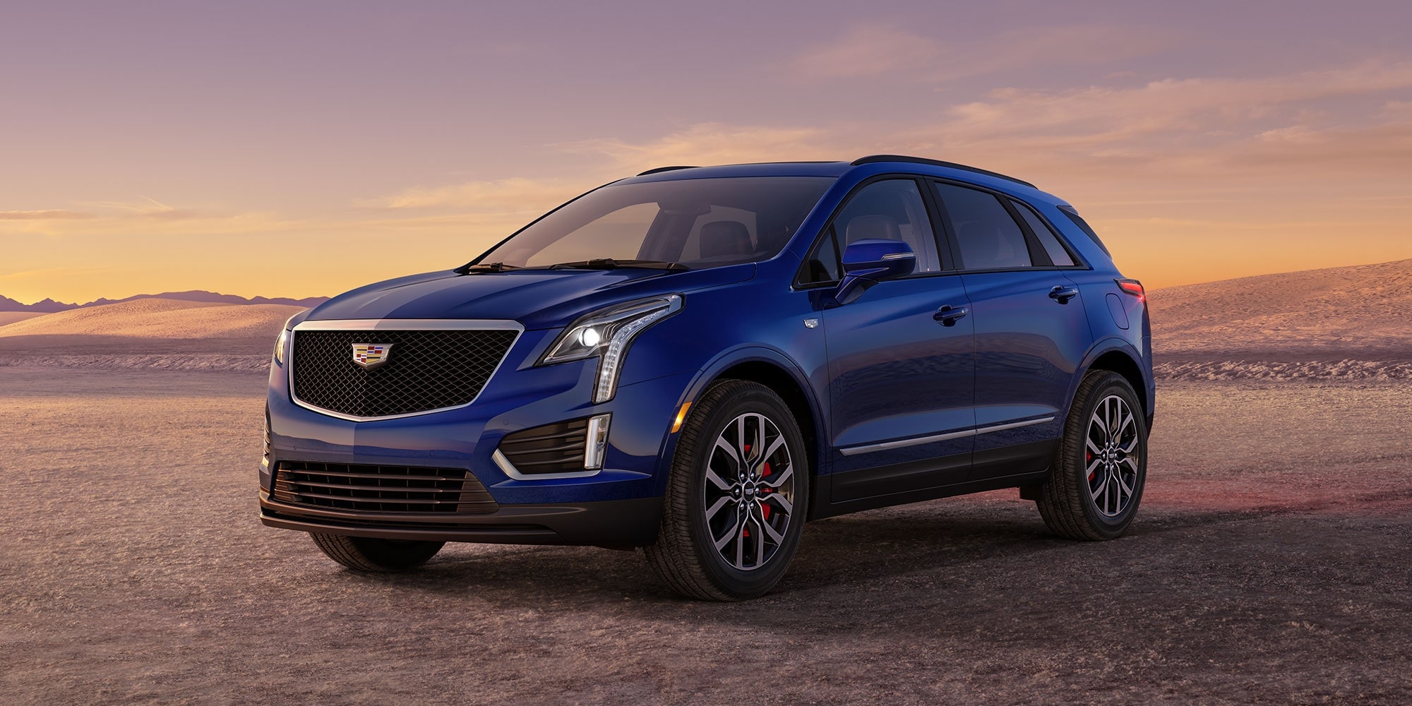 A blue Cadillac XT5 parked in a desert landscape