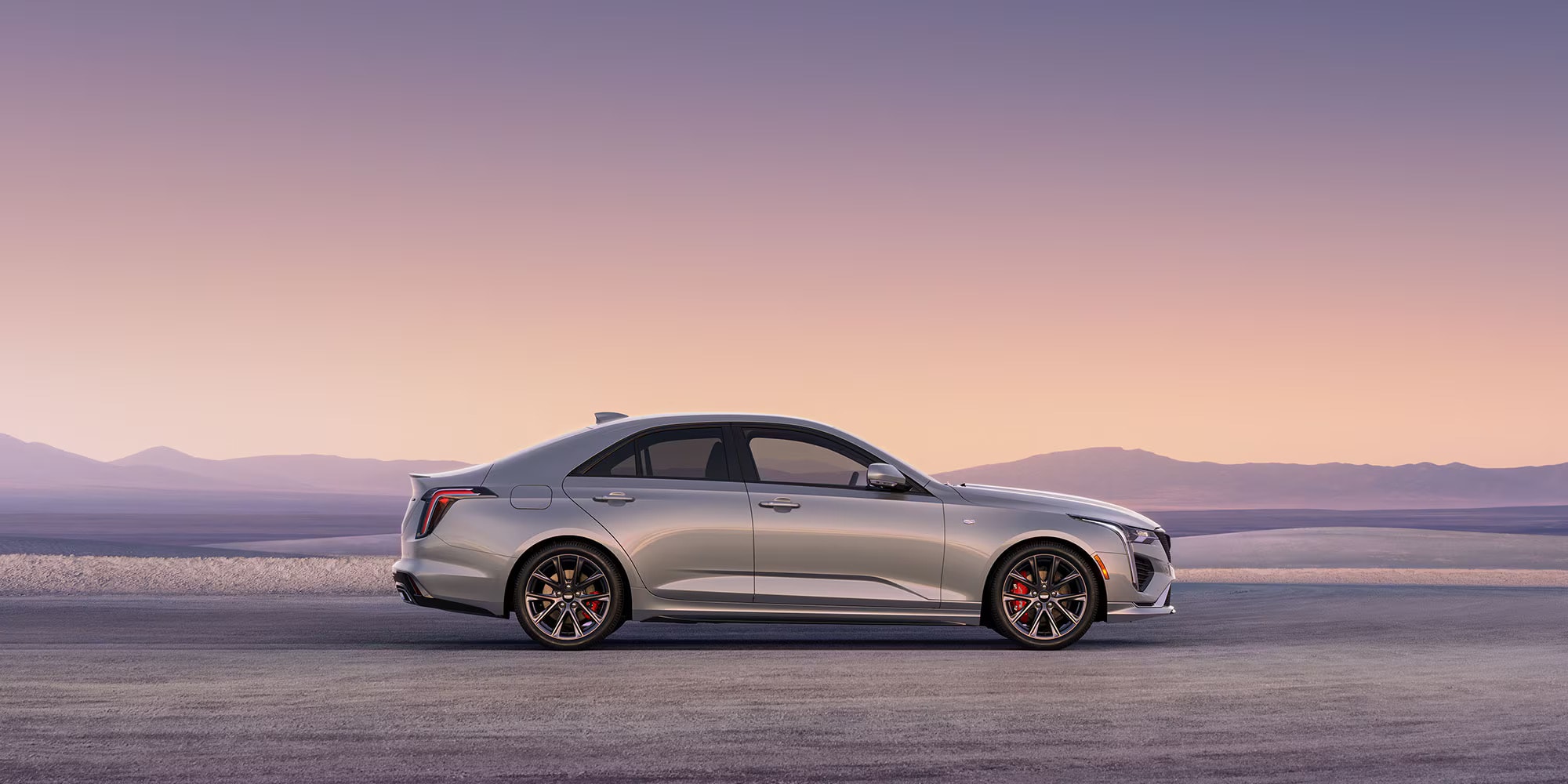 A silver Cadillac CT4 in profile against a flat, desert landscape