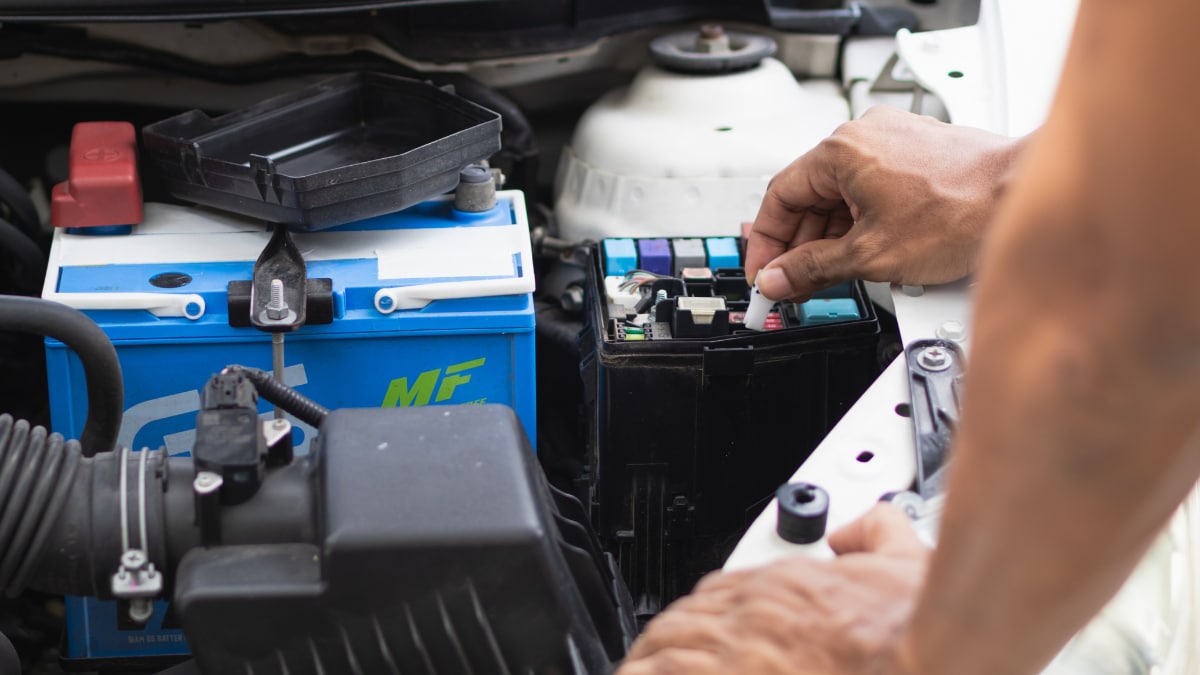 A mechanic examining a vehicle's battery and engine block