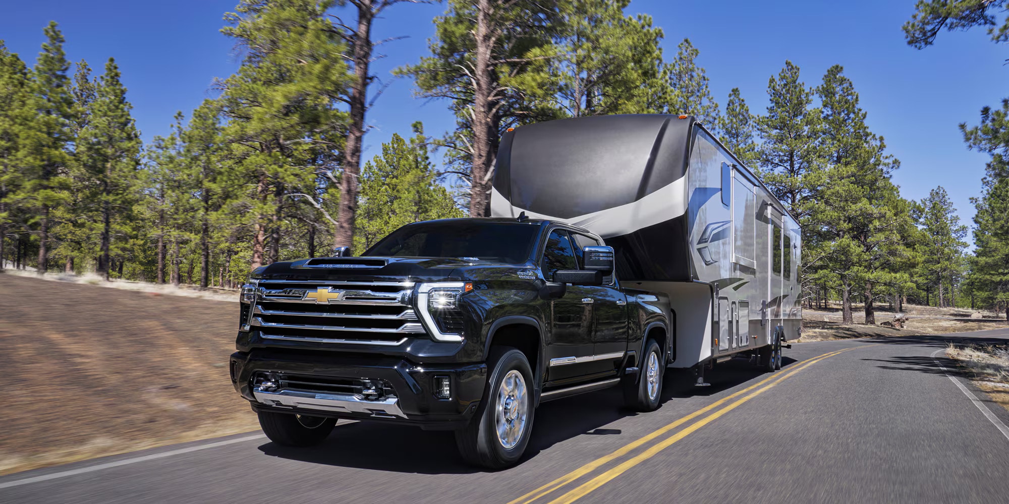 A black Chevrolet Silverado 2500 towing a trailer down the road