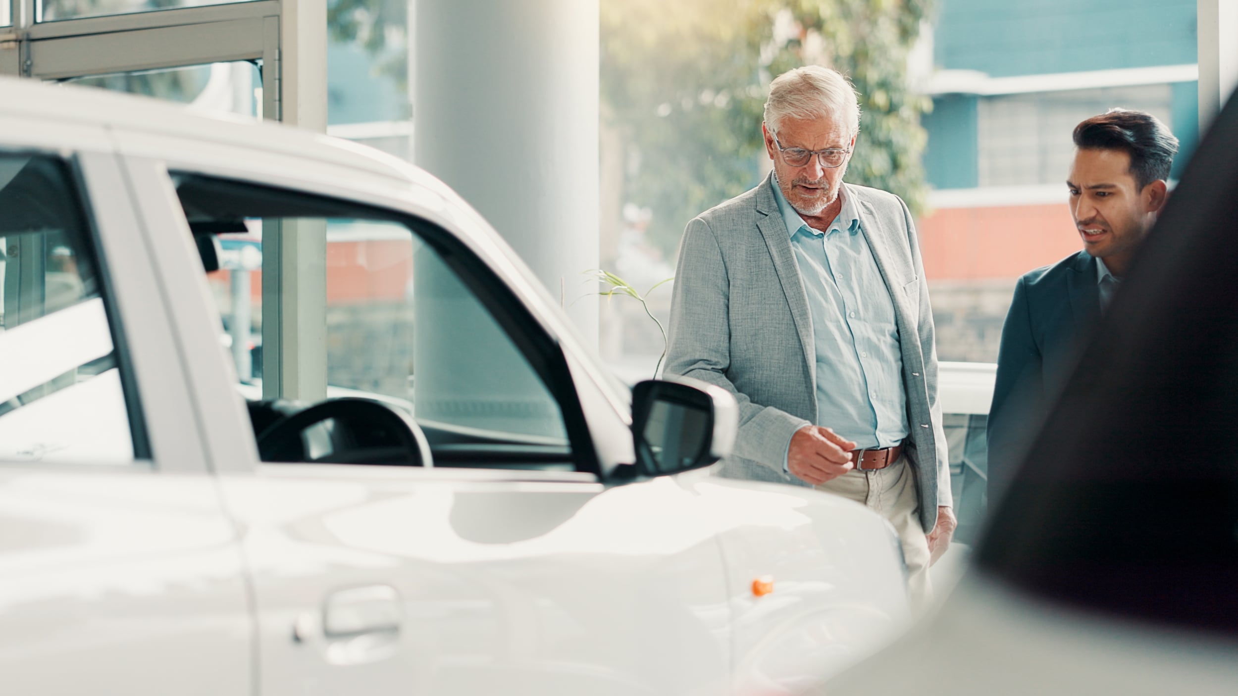 A salesperson showing another man their inventory of vehicles inside a dealership