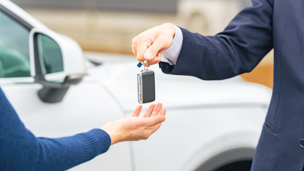A salesperson handing a car key fob to a customer