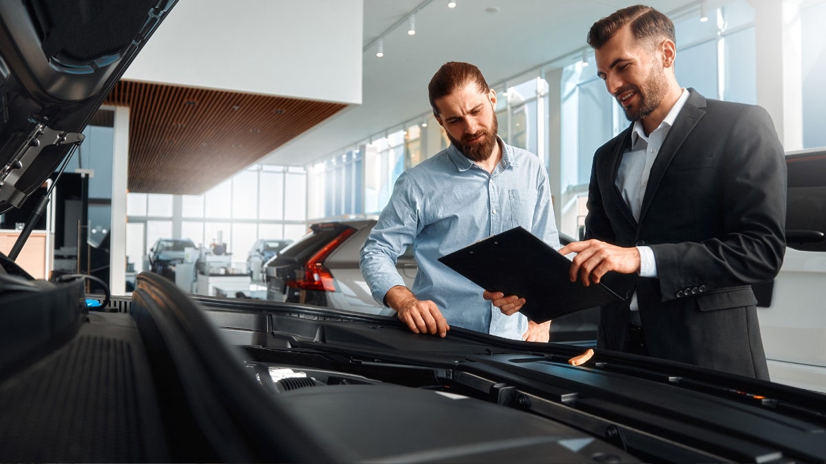 A salesperson showing a customer under the hood of a vehicle