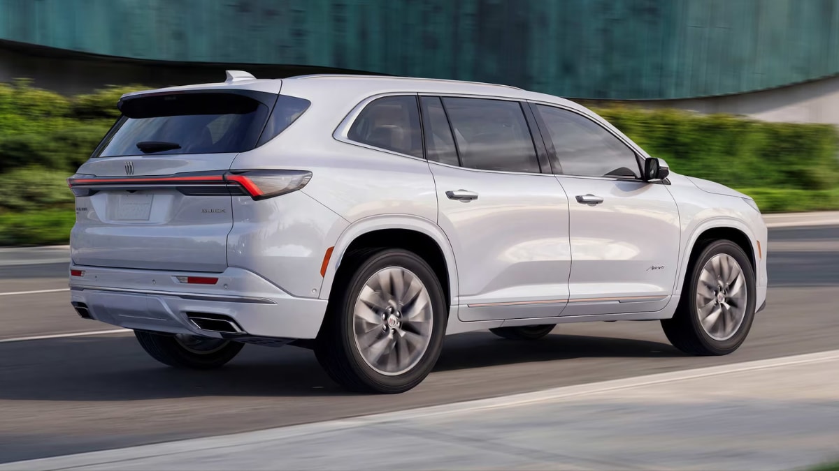 A side view of a silver Buick Enclave driving down the road