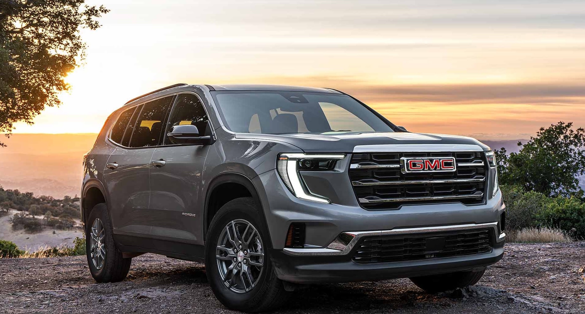 A gray GMC Acadia parked off-road facing away from a cliffside