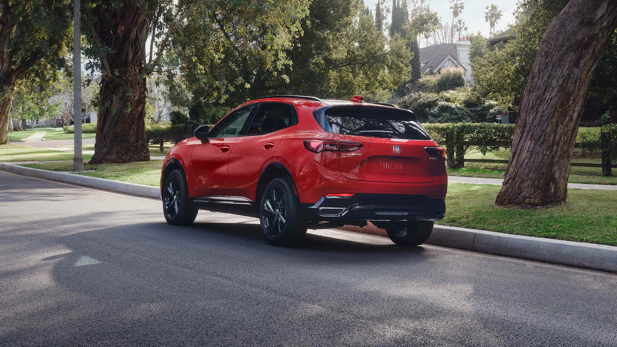 A red Buick Envision parked by the curb in a suburb