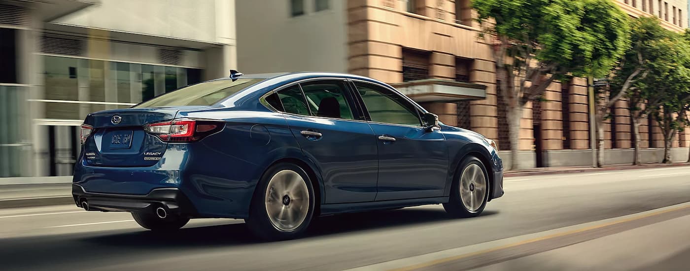 A blue 2022 Subaru Legacy Touring XT is shown from a rear angle driving through a city.
