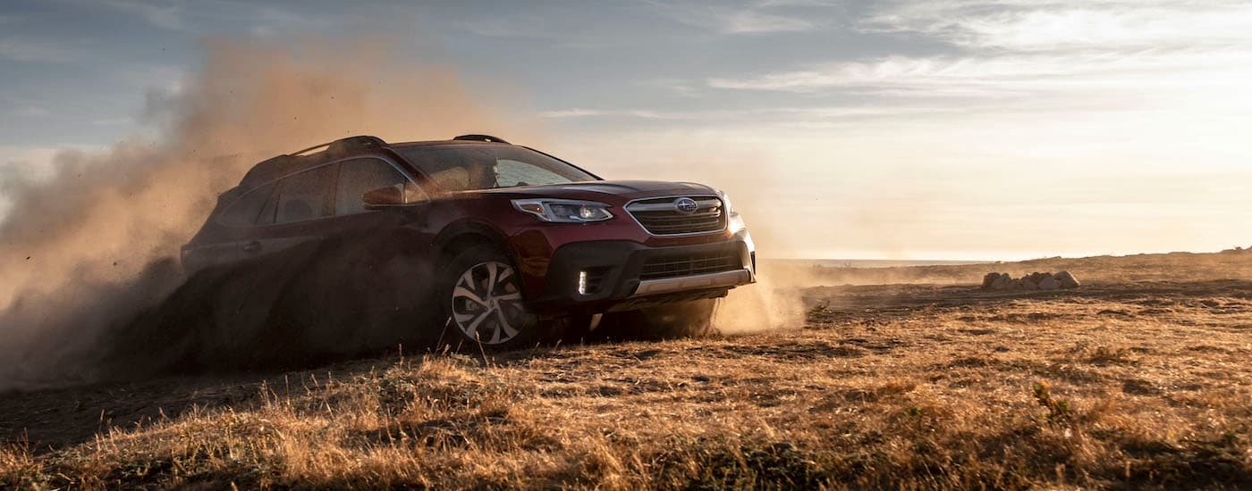 A red 2020 Subaru Outback is shown kicking up dust.