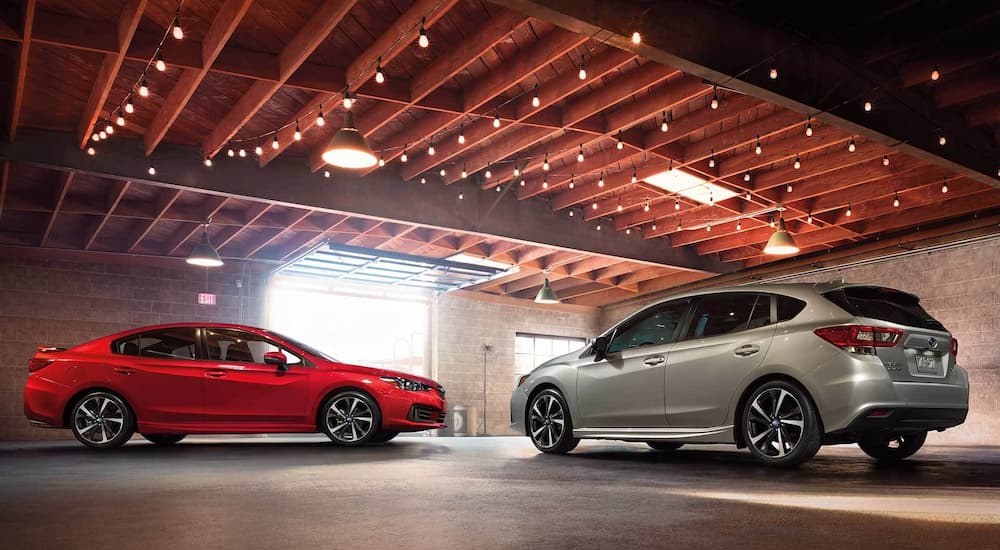 Subaru Dealership Near Albany - 2022 Subaru Impreza Sport - Duo.jpg A red and a silver 2022 Subaru Impreza Sport are shown facing each other in garage after visiting Subaru dealership near Albany.