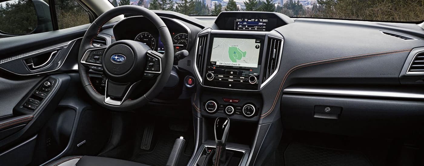 The black interior of a 2022 Subaru Crosstrek Limited shows the steering wheel and infotainment screen.