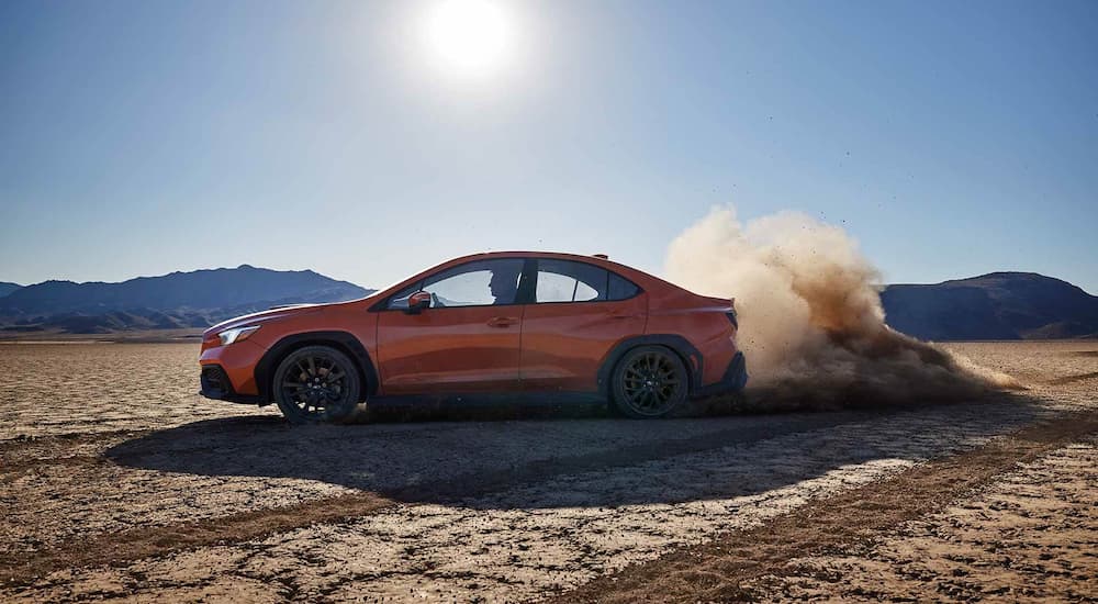 An orange 2022 Subaru WRX Limited is shown kicking up dust after leaving a Subaru dealer near you.