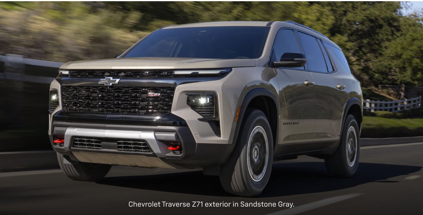 Front three-quarter view of a sand Chevrolet Traverse Z71 driving down a sunny asphalt road.
