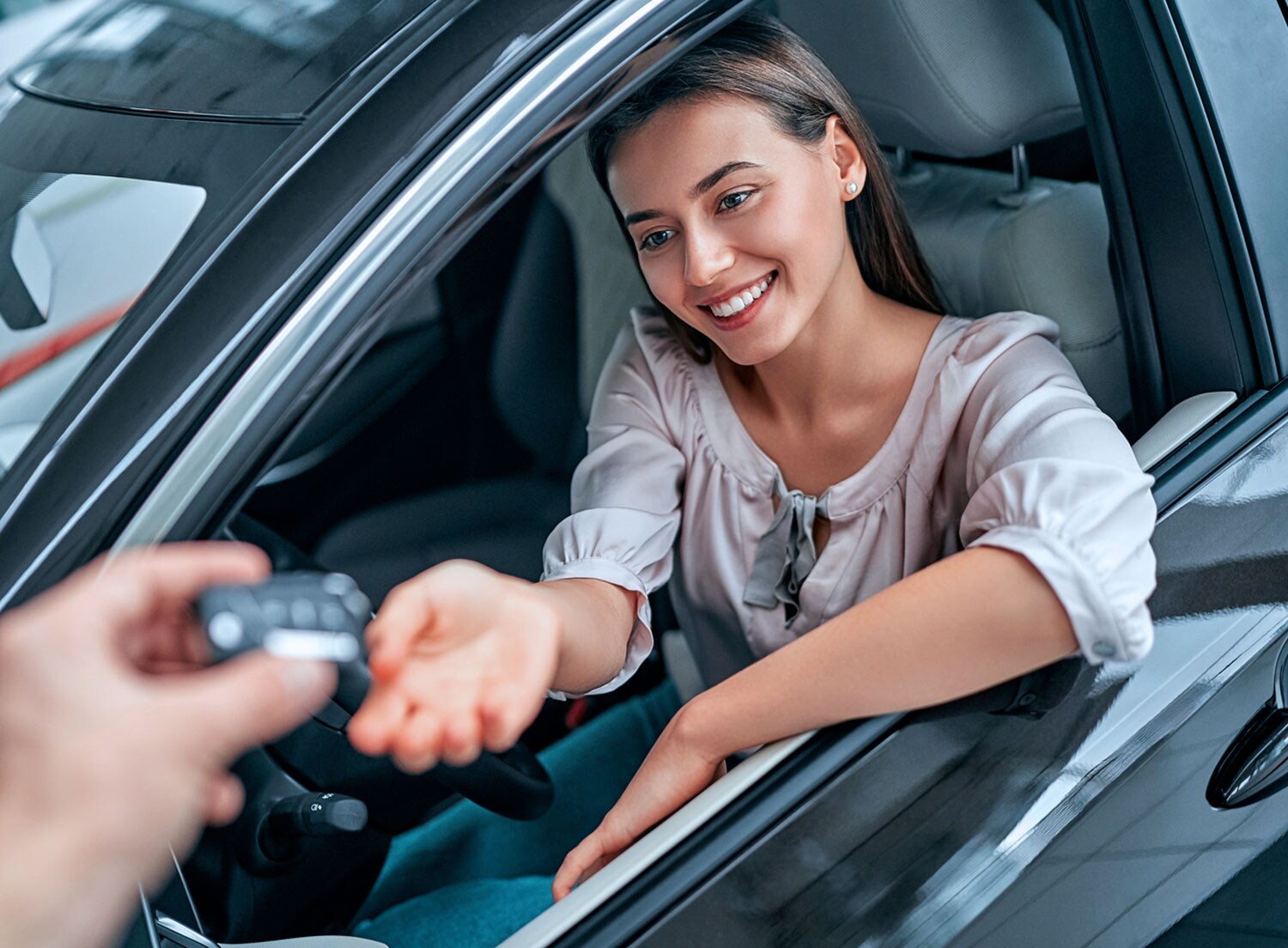 woman sitting in driver's seat of vehicle being handed keys