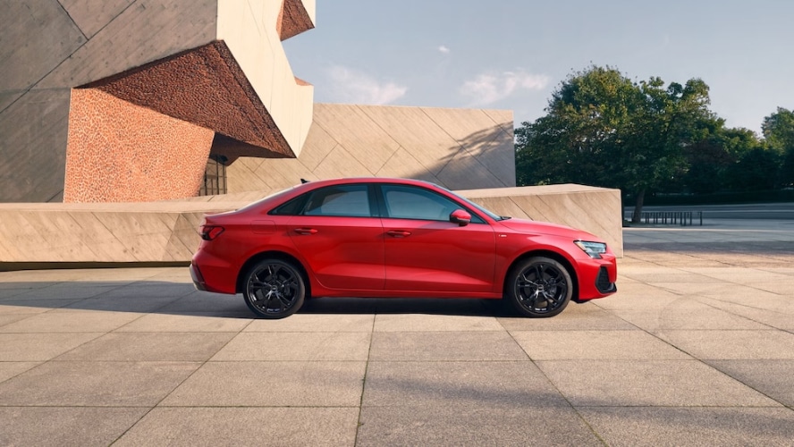 A red 2026 Audi A3 sedan parked outside a modern building