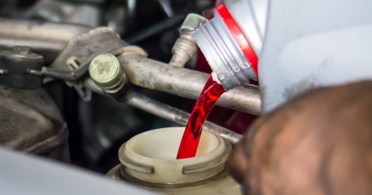 a hand pouring transmission fluid in a car.jpg