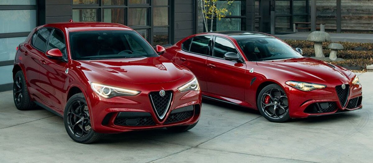 Red Alfa Romeo Giulia and Stelvio parked in front of house.