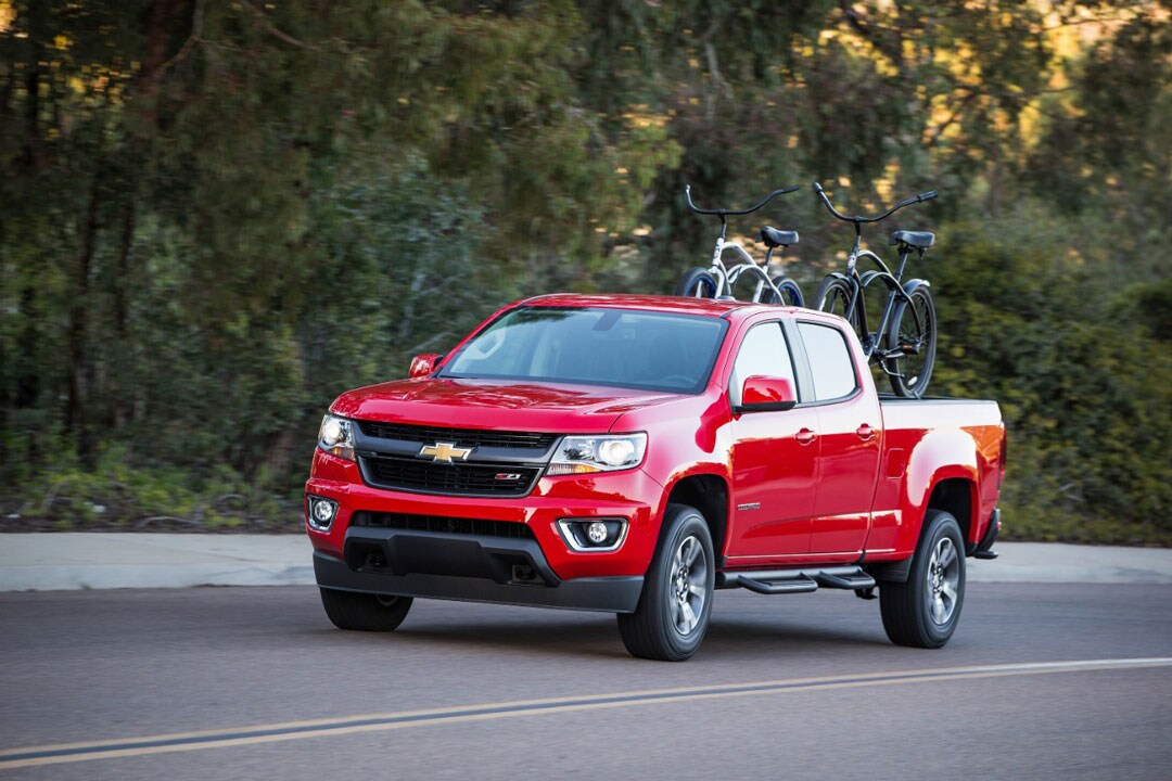 vue trois quart avant du Chevrolet Colorado 2018 roulant sur une route avec deux vélos dans la boîte
