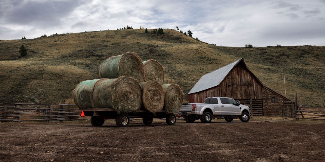 vue latérale arrière du Ford F-350 stationné sur une ferme avec une remorque de botte de foin