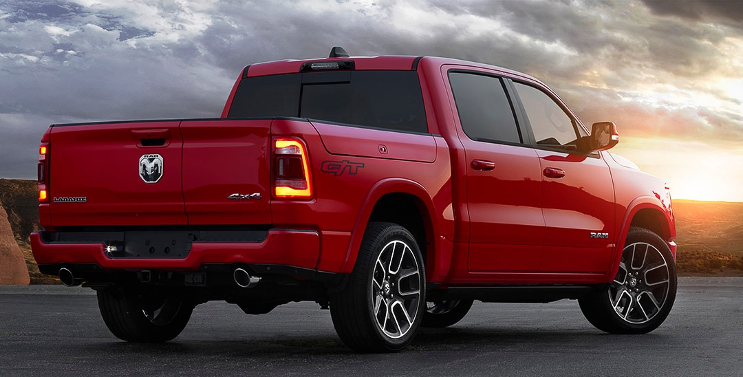 Vue 3/4 arrière d'un RAM 1500 Laramie G/T 2022 rouge garé non loin d'un canyon au crépuscule