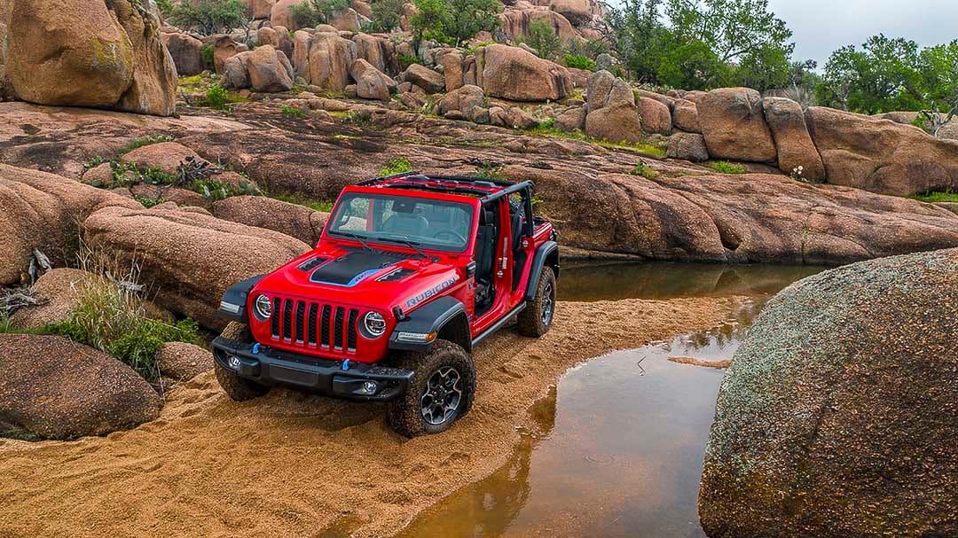three quarter front view of the 2022 Jeep Wrangler 4xe parked next to a stream