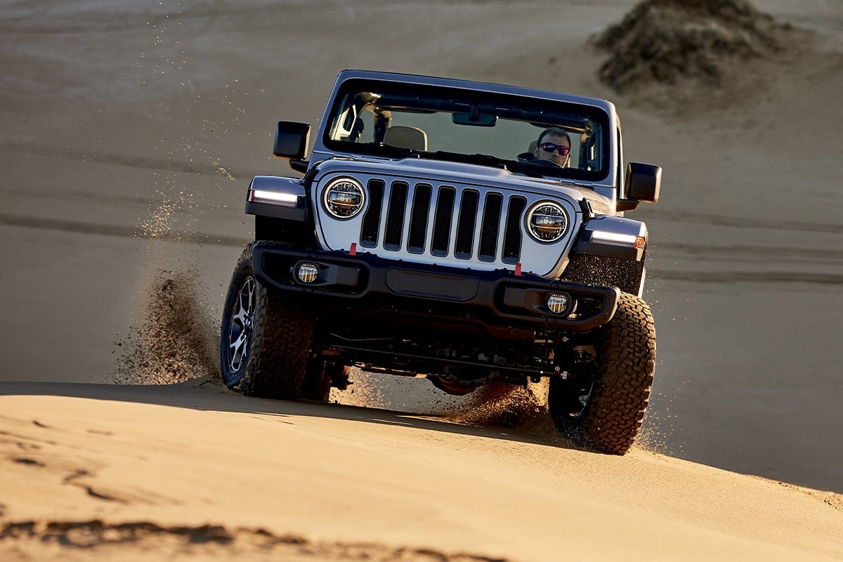 Front view of a Jeep Wrangler with BFGoodrich off-road tires drifting in the sand