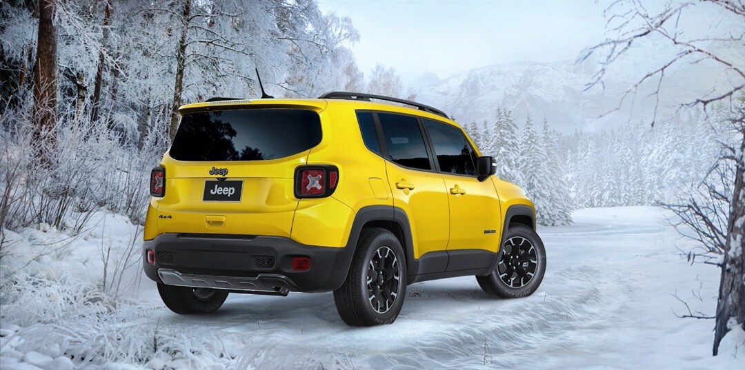 Rear 3/4 view of the Solar Yellow 2023 Jeep Renegade parked outside in the winter season.